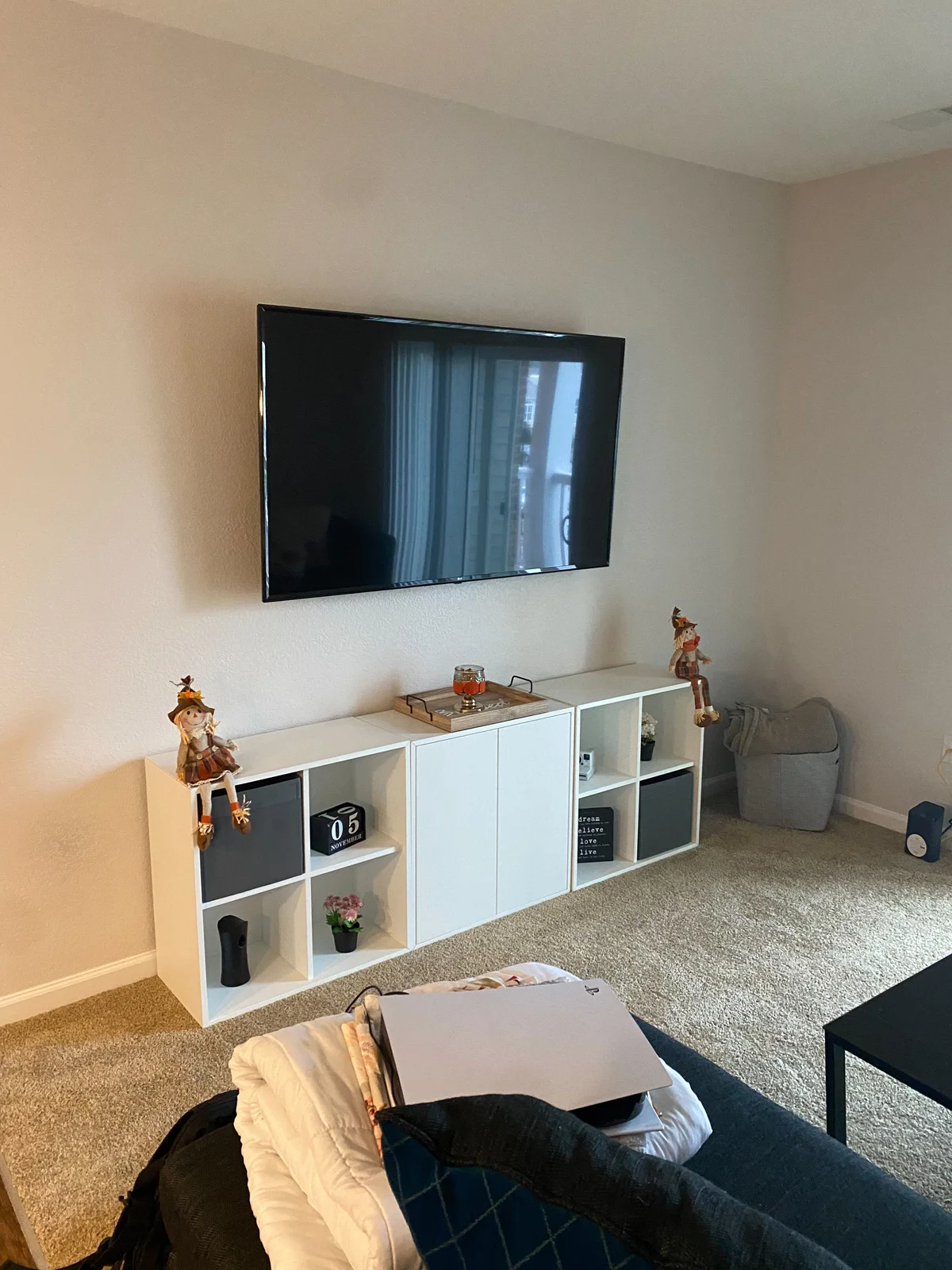 Wall-mounted television with no visible cable below the screen above a white cube-storage console.