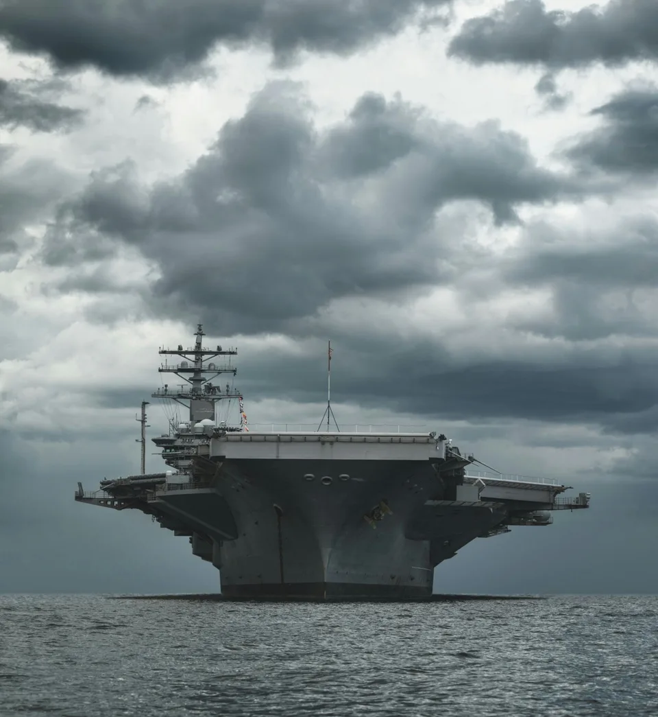 Aircraft carrier viewed from the bow beneath a cloudy sky